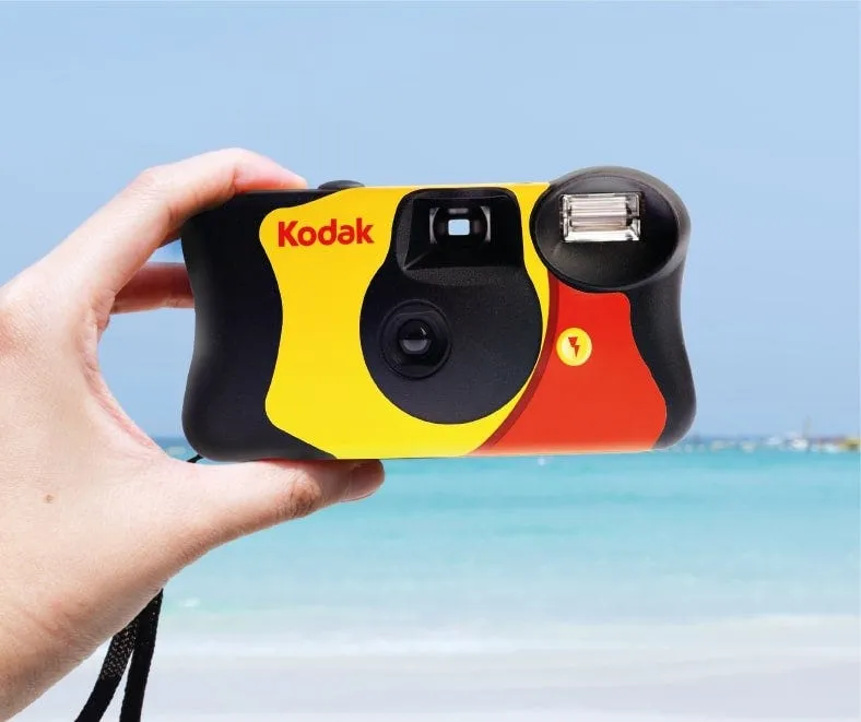 A disposable camera held up at the beach