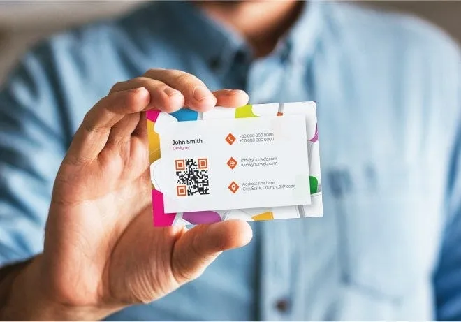 A hand holding a set of printed business cards